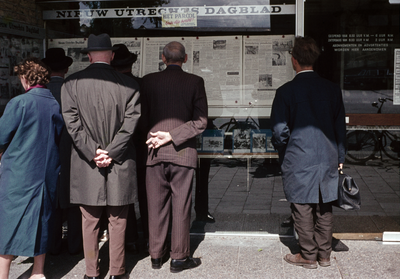 849782 Afbeelding van enkele personen die de krant lezen in de vitrines van het kantoor van het Nieuw Utrechts Dagblad ...